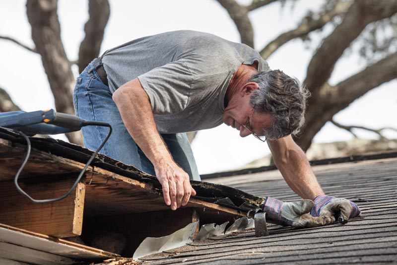 Uomo che lavora in altezza per la riparazione del tetto